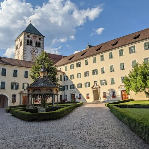 Scoprire l’Alto Adige da Maranza: giornate in montagna davanti alla porta ed escursioni a Bressanone, in Val Pusteria e nelle Dolomiti. Pianifica la tua vacanza.. Cortile storico con torre dell’orologio, fontana a padiglione e siepi curate