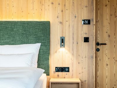 Schlafzimmer im Design-Apartment der Mountain Lodge Margit in Meransen, Südtirol Schlafzimmer mit Doppelbett, grün gepolstertem Kopfteil und Holzverkleidung im Design-Apartment der Mountain Lodge Margit in Meransen, Südtirol.
