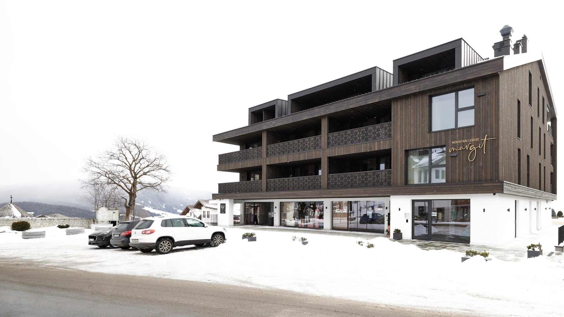 Beispielaufbau einer Unterseite Modern mountain lodge building with parking and snow in winter