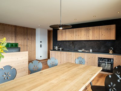 Ferienwohnung im Pustertal? Jetzt anfragen und los geht’s! ☎ Moderne Küche mit Holzfronten und Esstisch mit dekorativen Stühlen