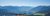 Frühbucher Bonus & Bestprice in Meransen / Südtirol | Mountain Lodge Margit Panorama-Ausblick vom Gitschberg über das grüne Eisacktal auf die fernen Berggipfel der Dolomiten in Südtirol an einem sonnigen Sommertag.